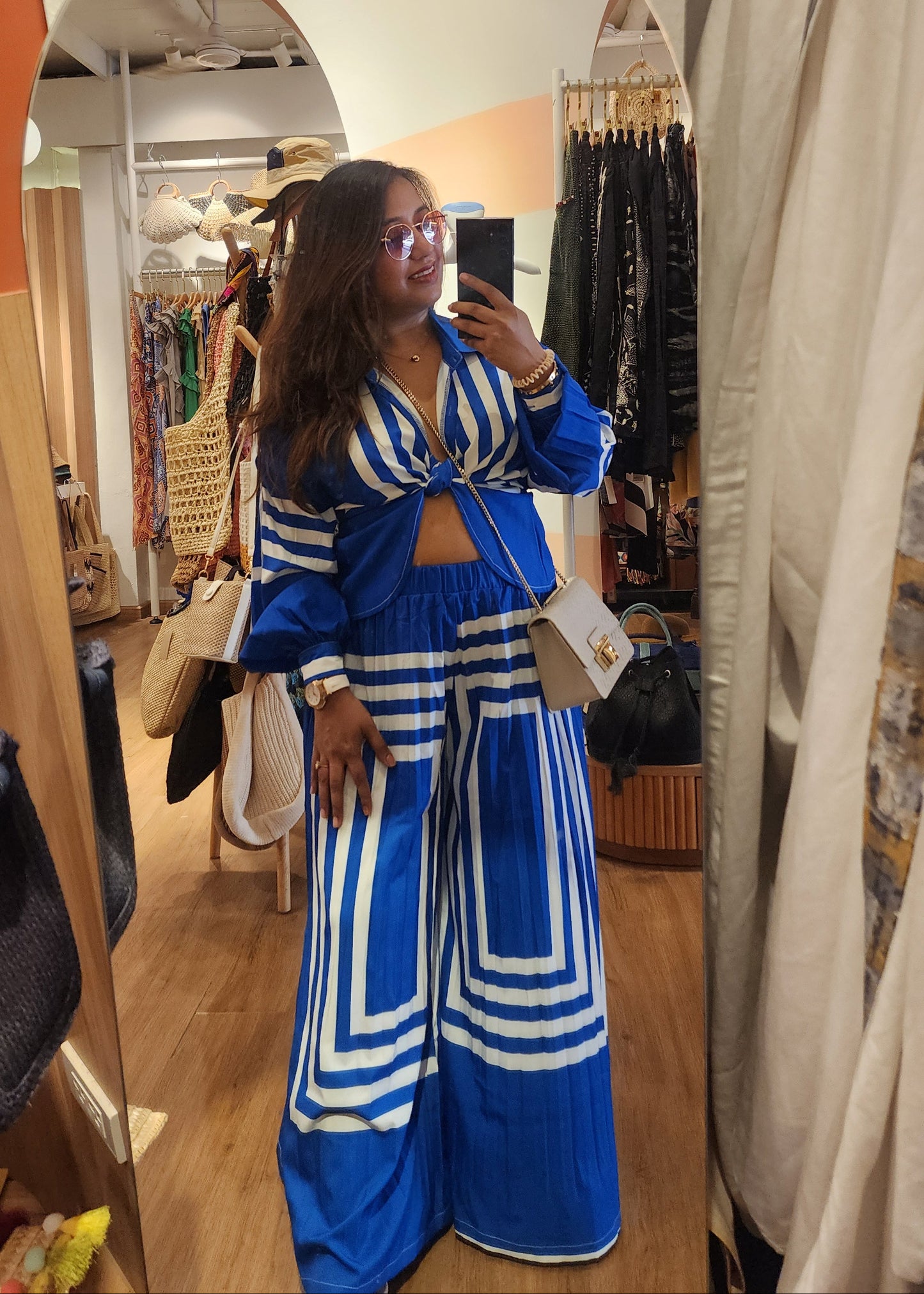 Woman in a blue and white outfit standing in front of a mirror in a store.