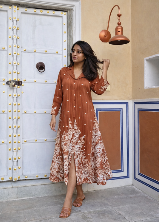 Woman in a rust-colored dress standing in front of a decorative door.