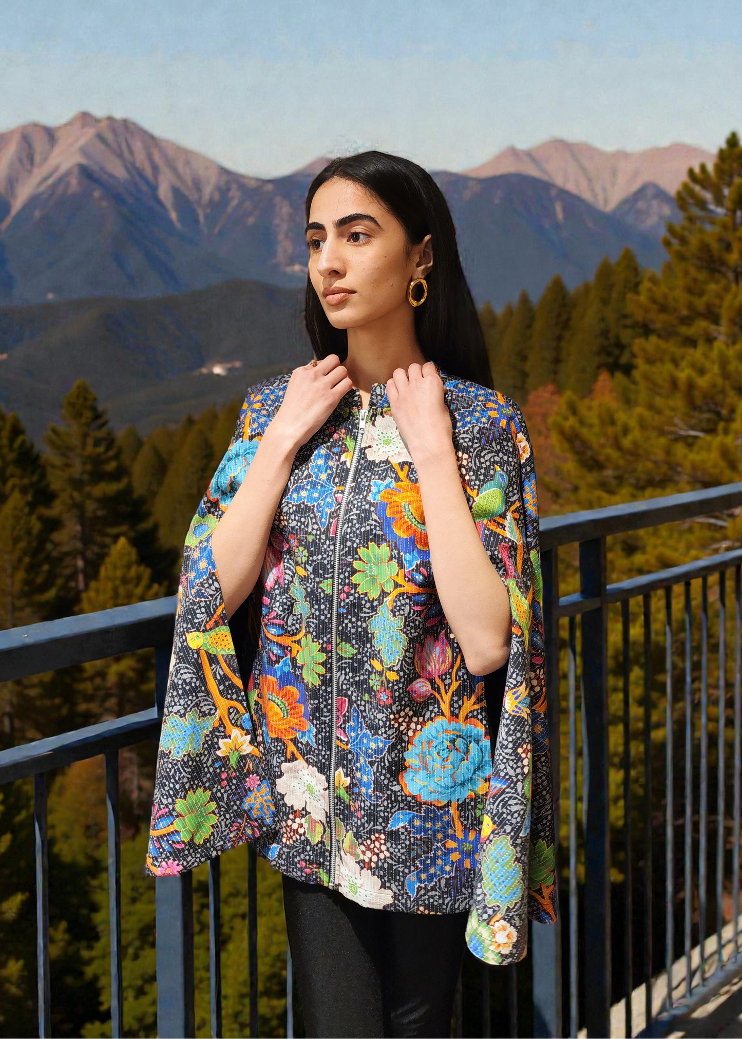 Woman wearing a colorful floral jacket with mountains and trees in the background