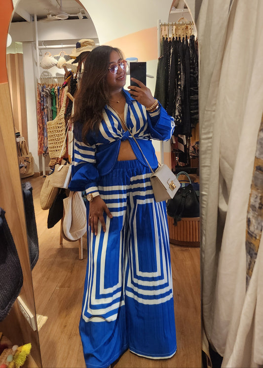 Woman in a blue and white outfit standing in front of a mirror in a store.