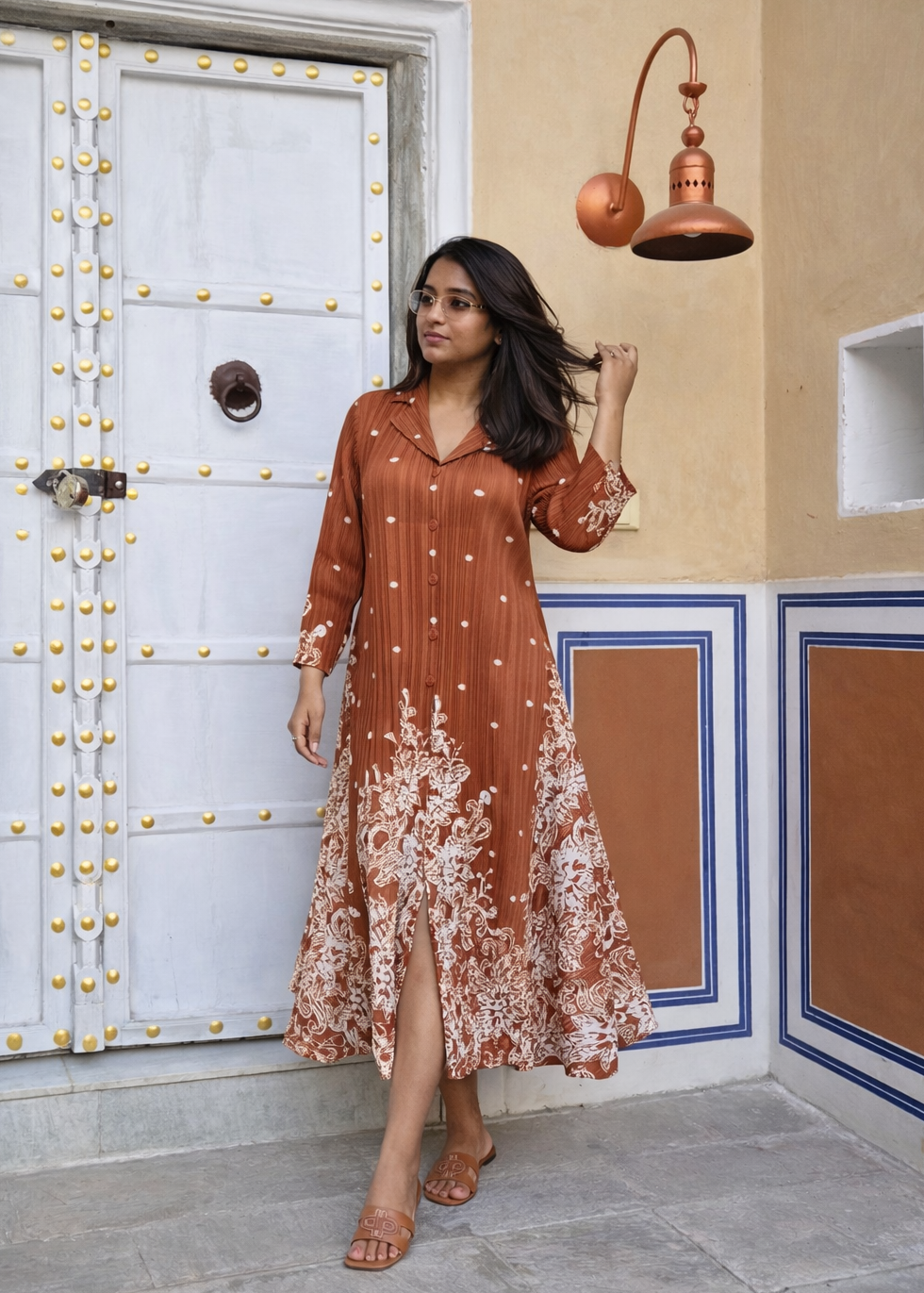 Woman in a rust-colored dress standing in front of a decorative door.