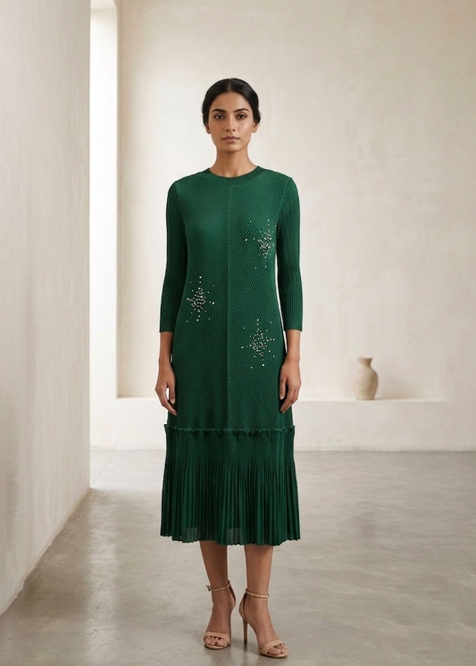 Woman wearing a green dress with intricate patterns in a minimalistic setting