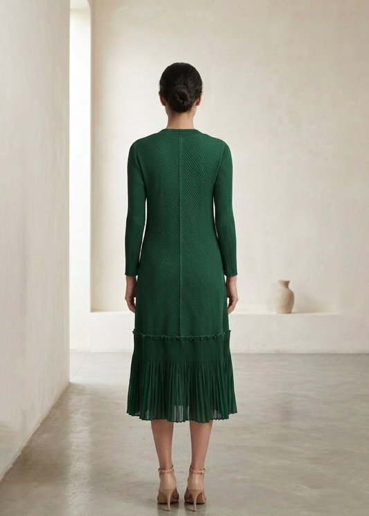 Woman wearing a green dress standing in a minimalistic room.