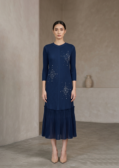 Woman wearing a navy dress with star patterns against a beige background