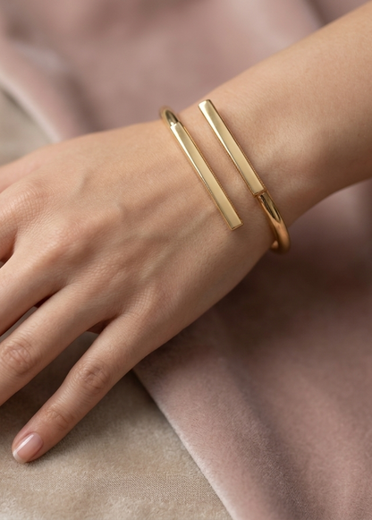 Gold bracelet on a wrist with a soft pink background