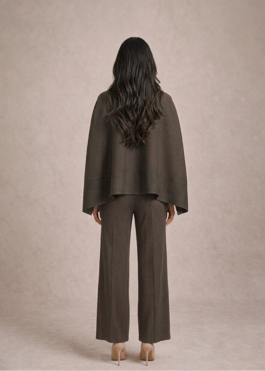 Woman wearing a brown suit standing against a beige background