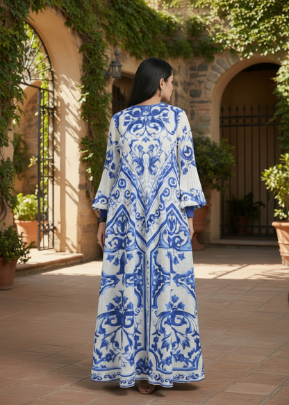 Woman wearing a blue and white patterned dress standing in an outdoor setting with greenery.