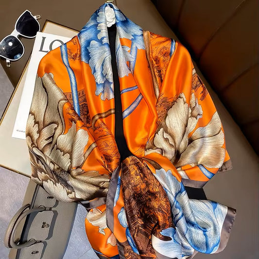 Colorful scarf with nature-themed design on a surface with sunglasses and a magazine.