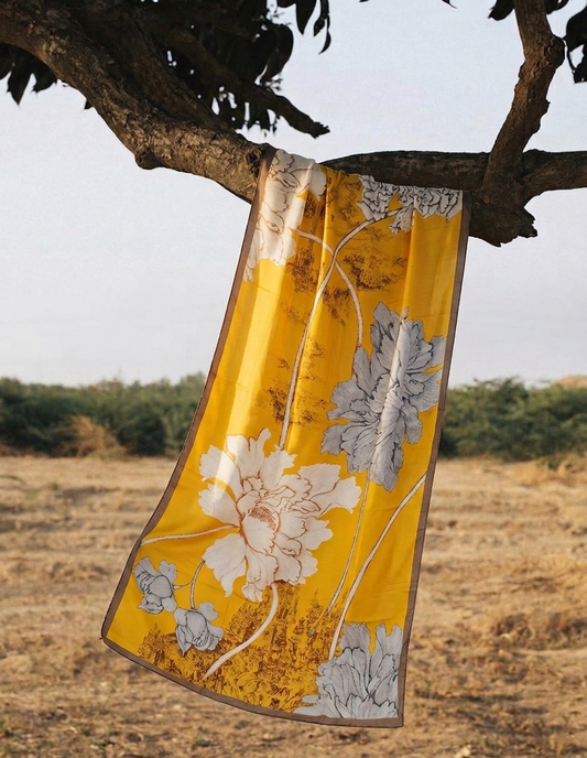 Floral-patterned fabric hanging from a tree branch with a natural landscape in the background