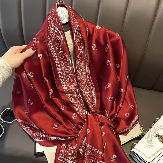 Red patterned scarf draped over a chair with sunglasses and a handbag in the background.