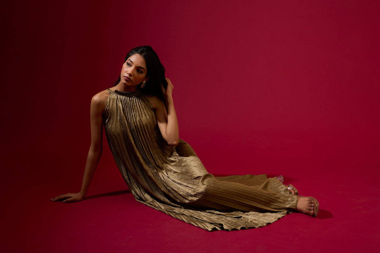 Woman in a gold dress sitting on a red background
