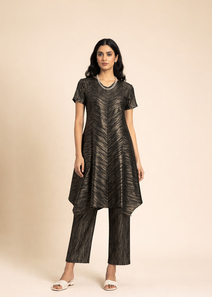 Woman wearing a black patterned dress with matching pants on a beige background